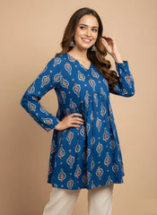 Woman wearing a blue patterned dress against a beige background