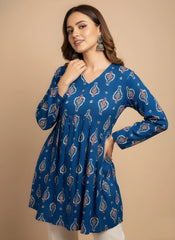 Woman wearing a blue patterned dress against a beige background