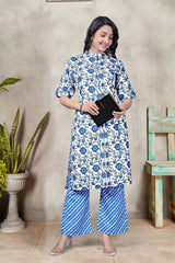Woman wearing a blue and white floral outfit standing against a textured wall.
