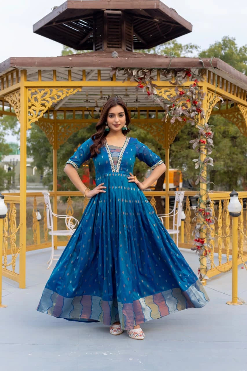 Woman in a blue traditional outfit standing in front of a decorative gazebo.