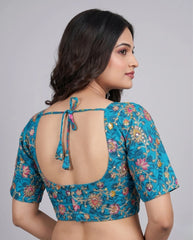 Woman wearing a blue floral blouse with an open back on a gray background