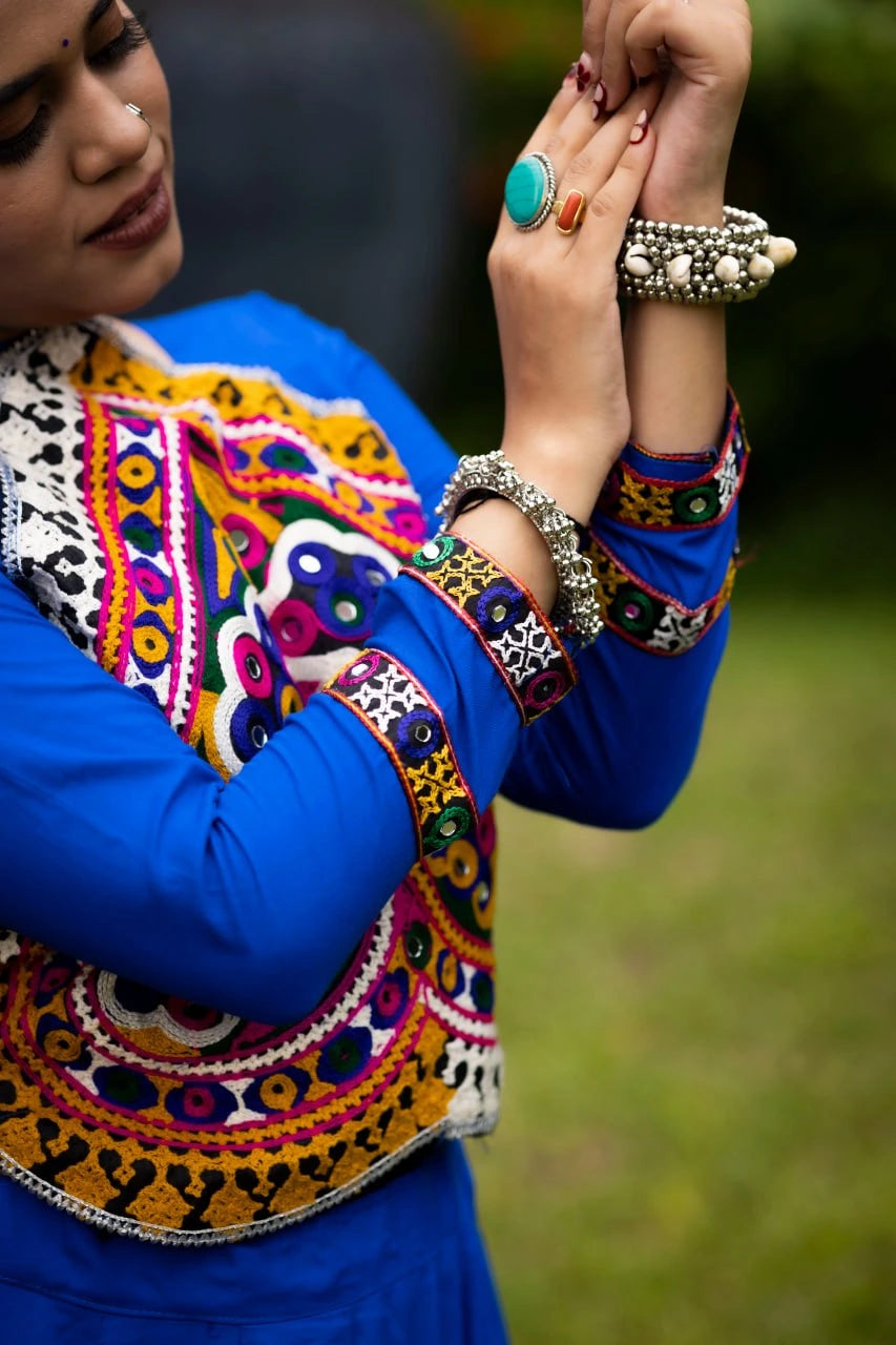 Woman wearing traditional embroidered attire with jewelry, outdoors.