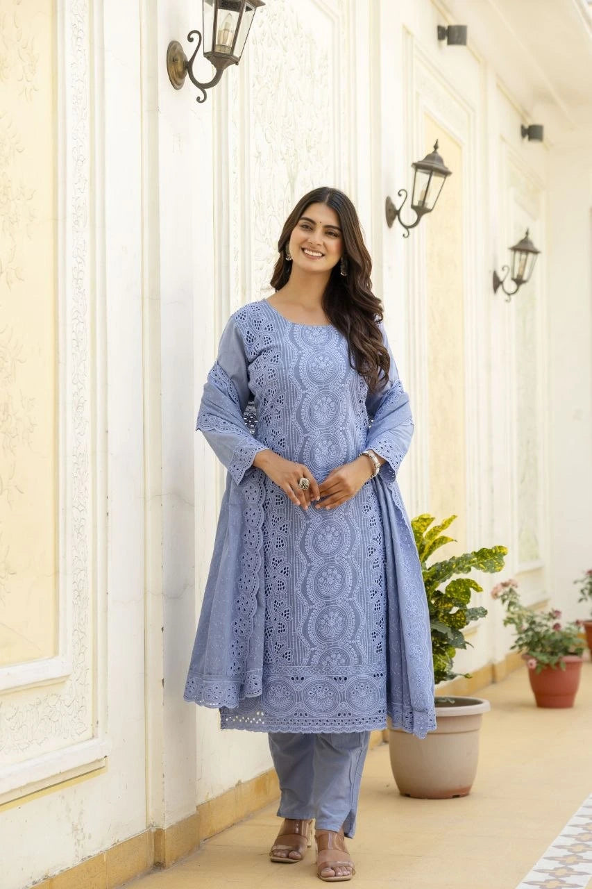 Woman wearing a blue embroidered outfit standing in a decorative hallway.