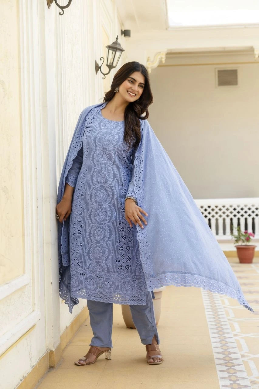 Woman in a blue embroidered outfit standing in a well-lit room.