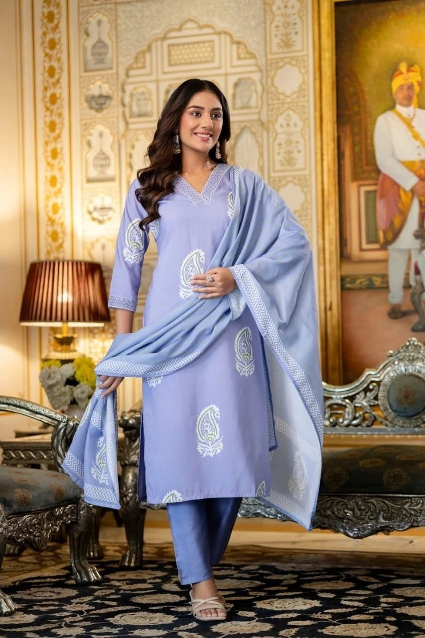 Woman in a light blue traditional outfit with white patterns in an ornate room.