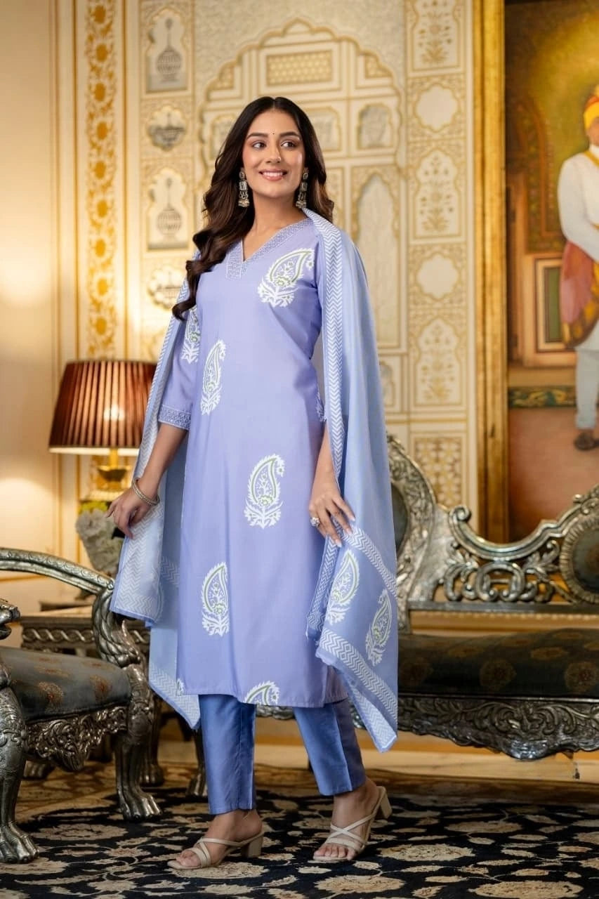 Woman in a light purple traditional outfit with white patterns in an ornate room.