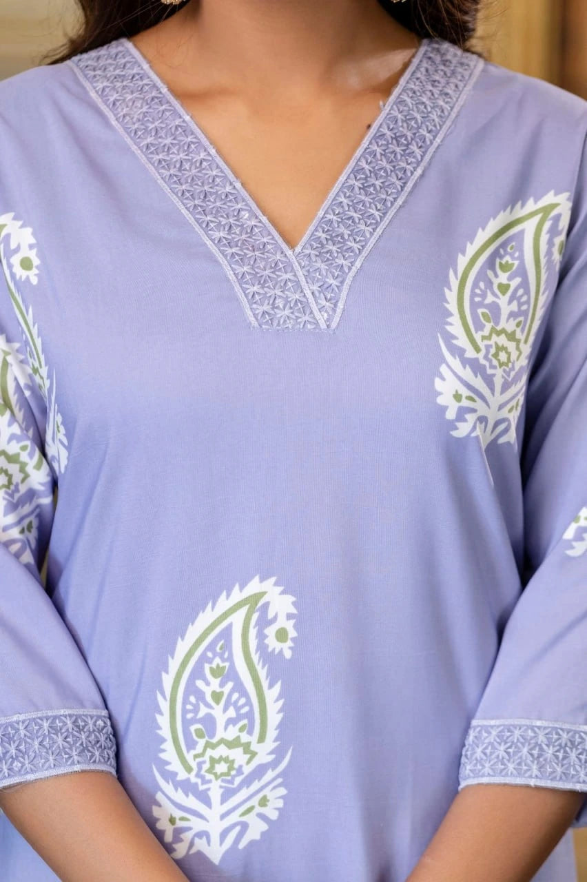 Light purple top with white and green floral embroidery on a blurred background