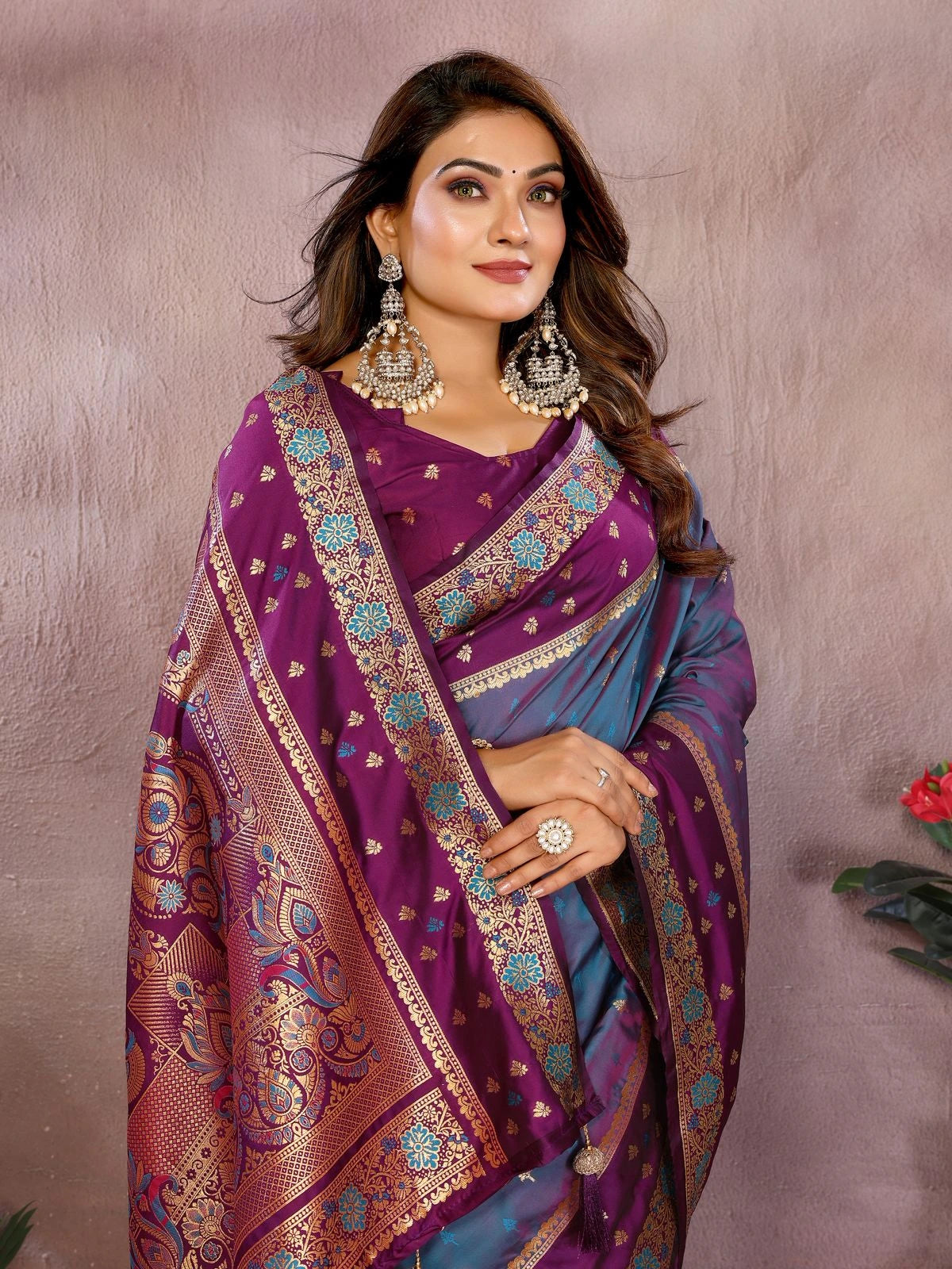Woman wearing a purple saree with a patterned border against a plain background