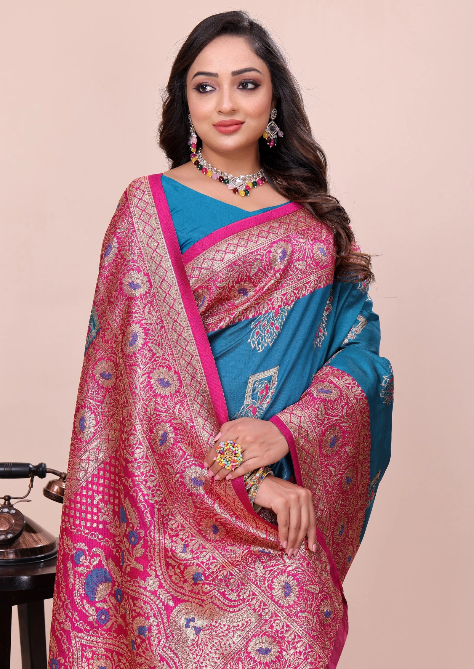 Woman wearing a pink and blue saree with a beige background