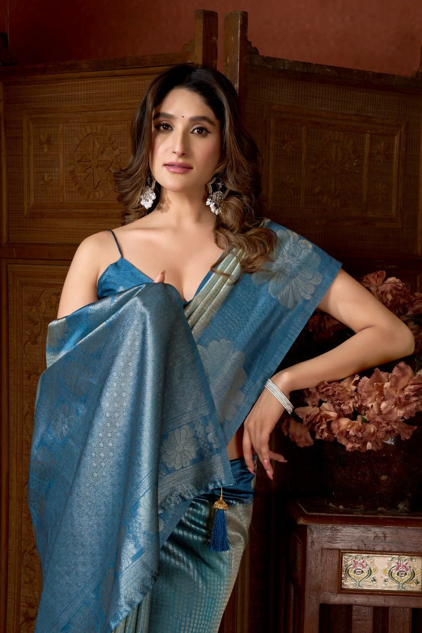 Woman in a blue saree posing indoors with wooden paneling.