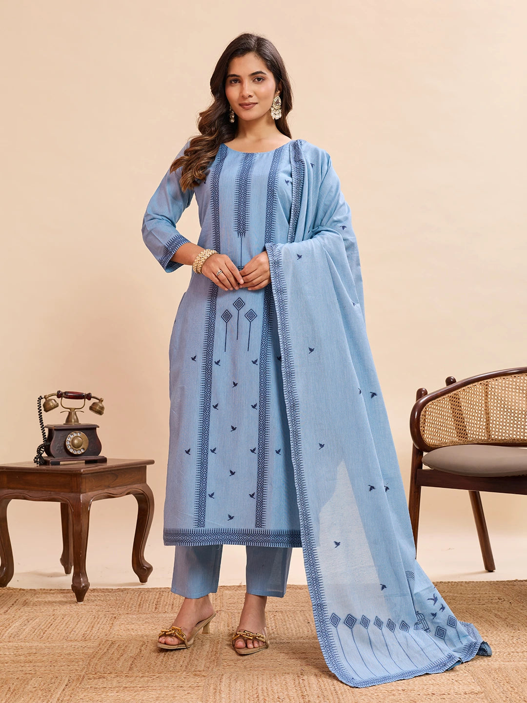 Woman wearing a light blue traditional outfit with a matching dupatta in a room setting.