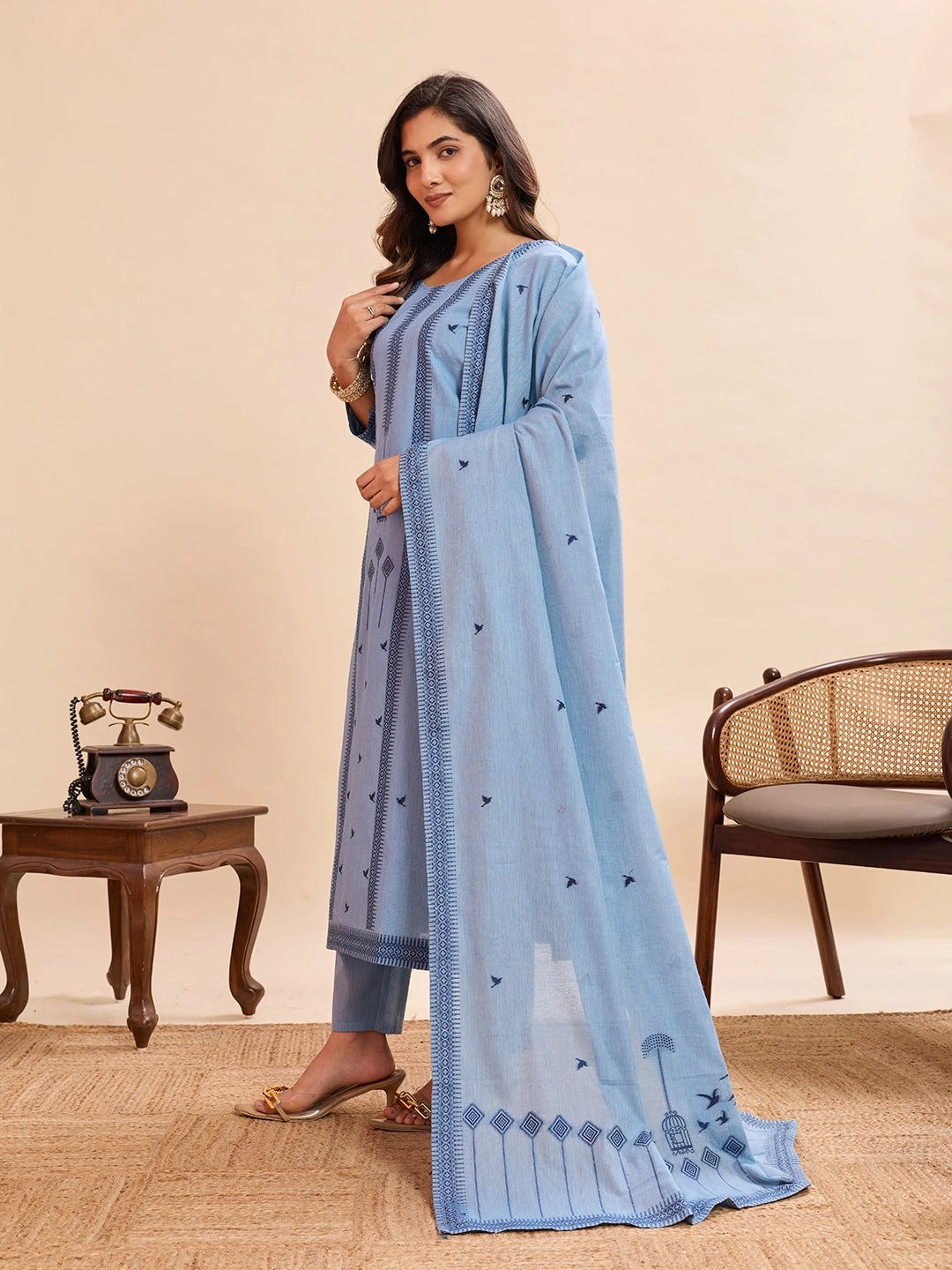 Woman wearing a light blue traditional outfit with a matching dupatta in a room setting.
