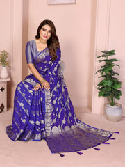 Woman wearing a blue saree with a white border in a room with plants.