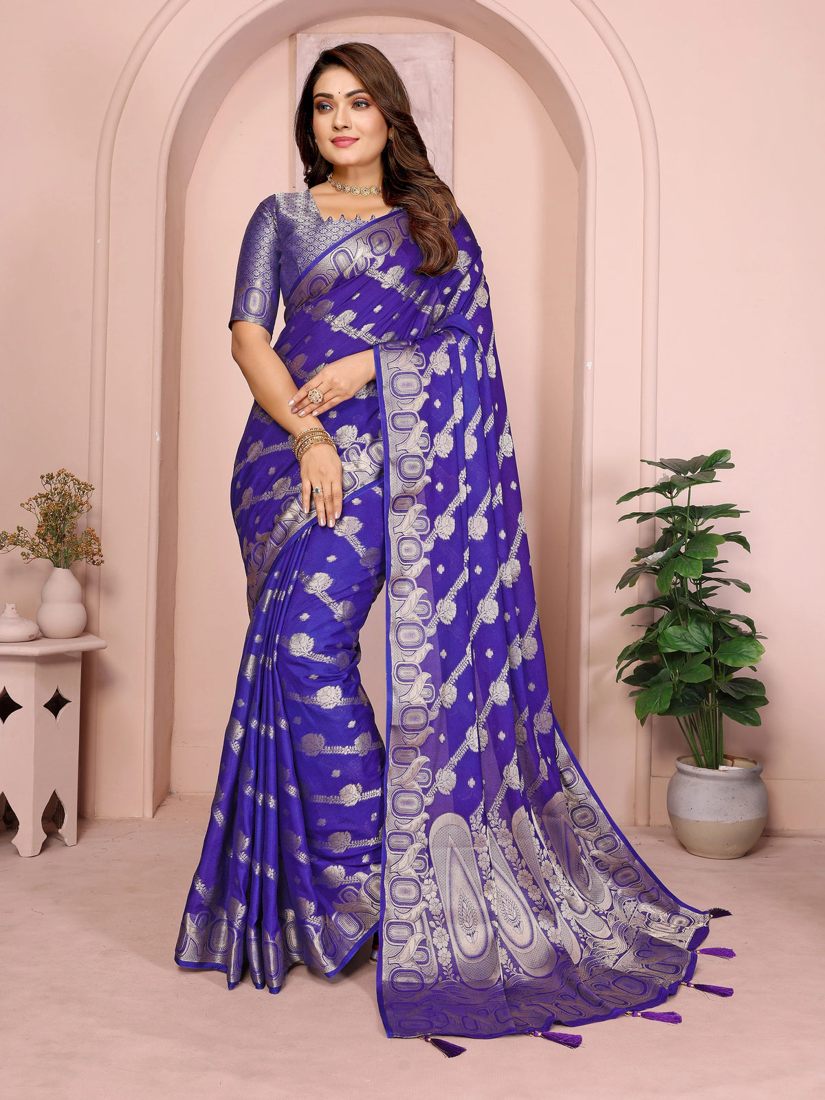 Woman wearing a blue saree with white patterns in an indoor setting.