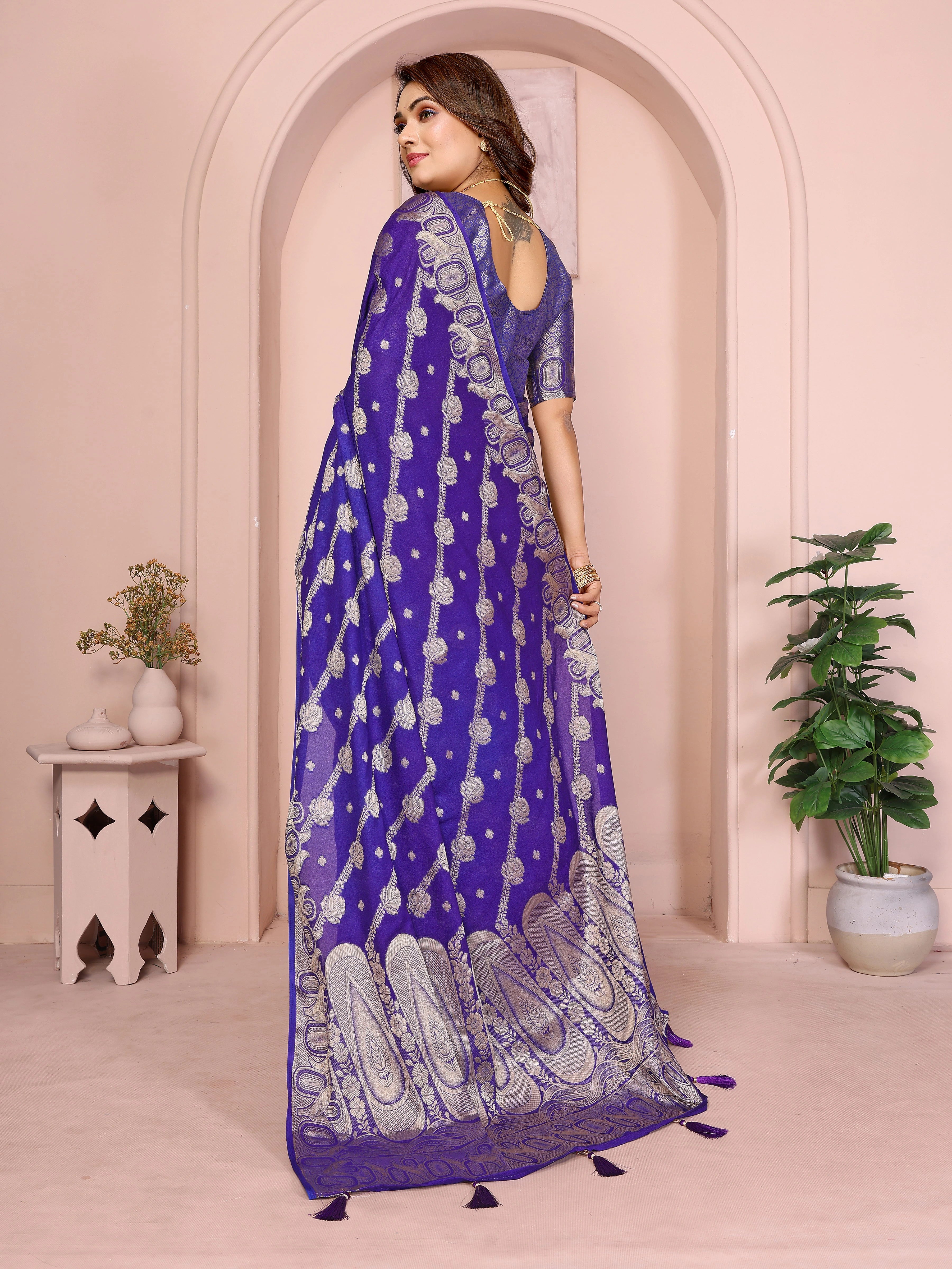Woman wearing a blue saree with white patterns in an indoor setting.