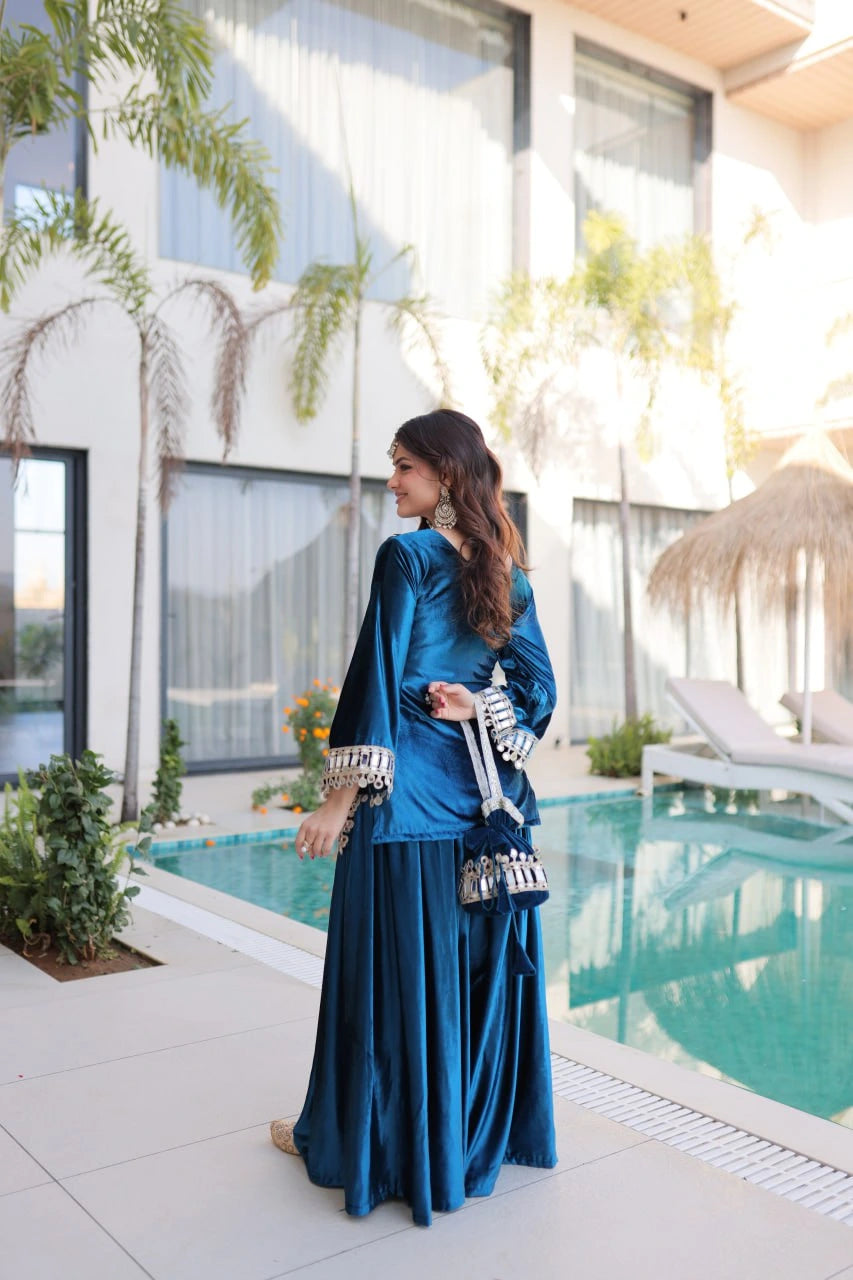 Woman in a blue traditional outfit standing by a poolside with modern architecture in the background