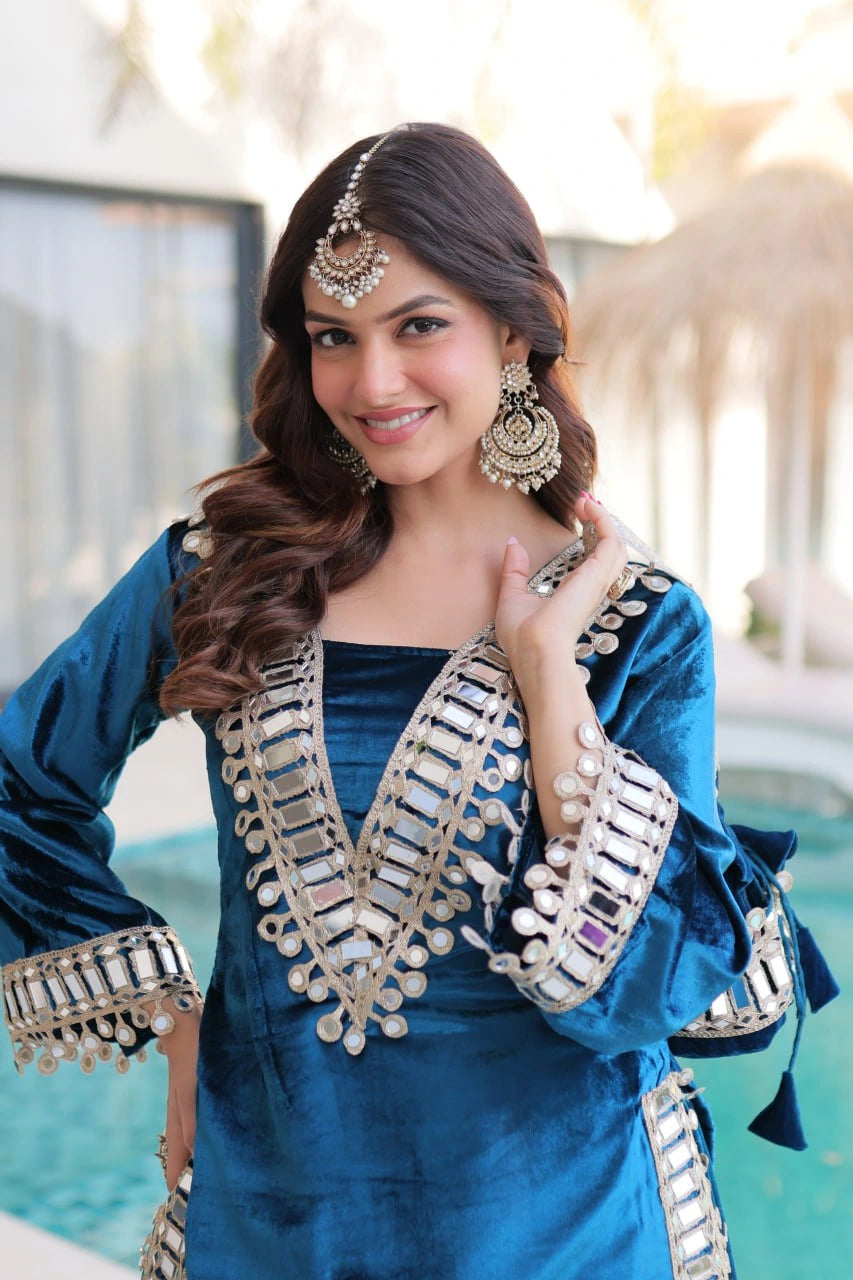 Woman in a blue traditional outfit with silver embroidery by a pool