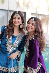 Two women in traditional attire with jewelry, standing close together outdoors.