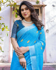 Woman wearing a blue saree with a floral pattern, standing outdoors.