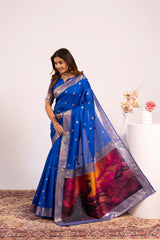 Woman wearing a blue saree with a colorful pattern on a white background