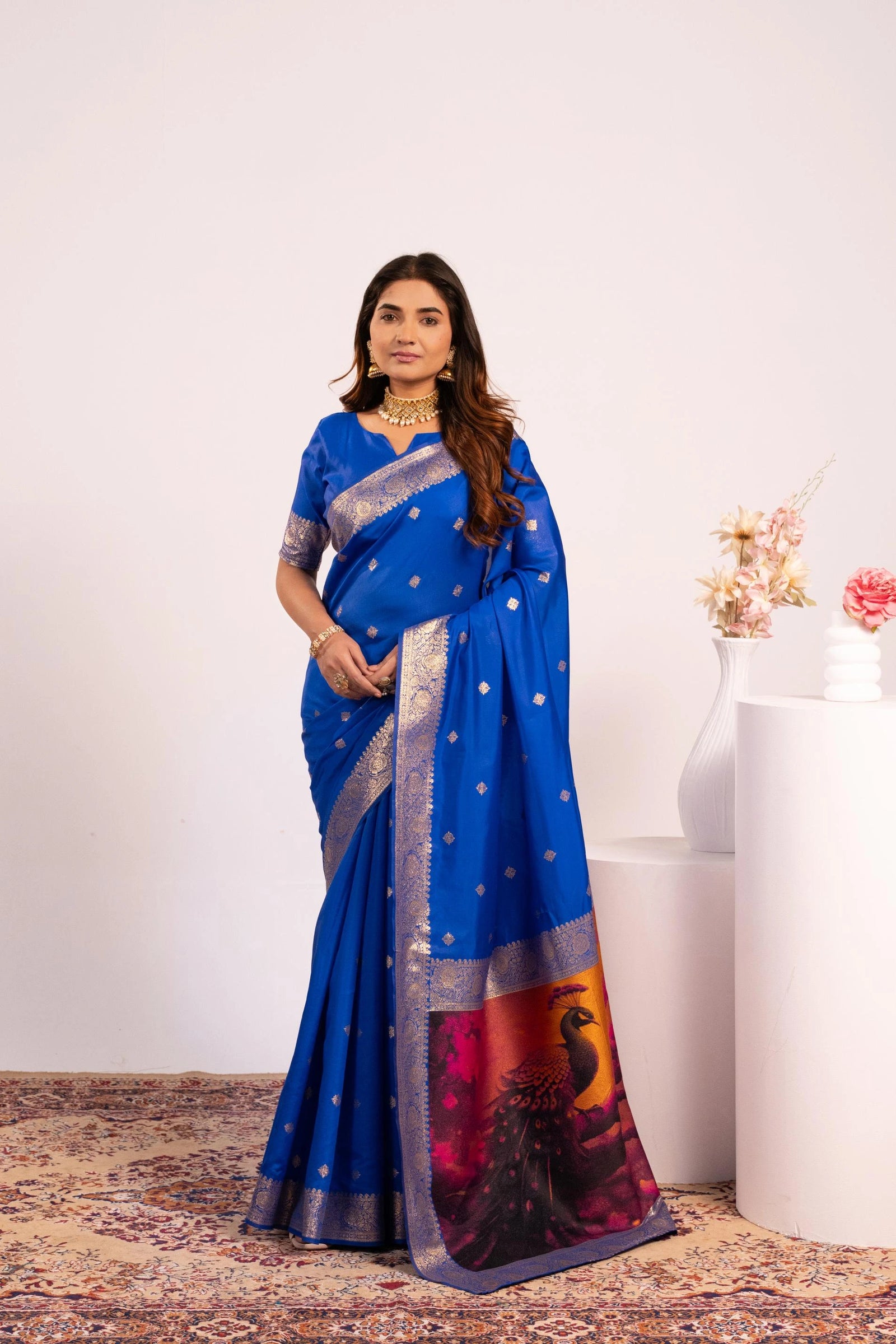 Woman wearing a blue saree with a peacock design on a white background