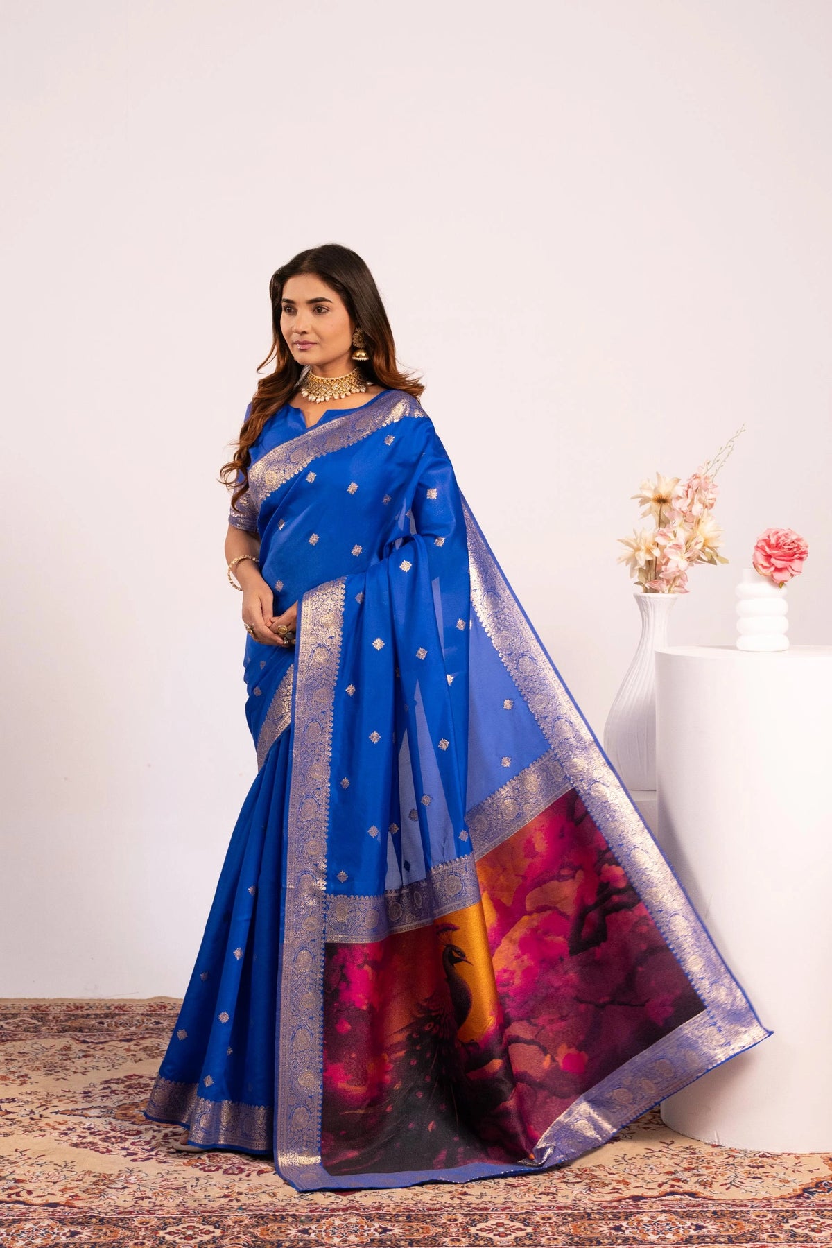 Woman wearing a blue saree with a colorful border against a white background
