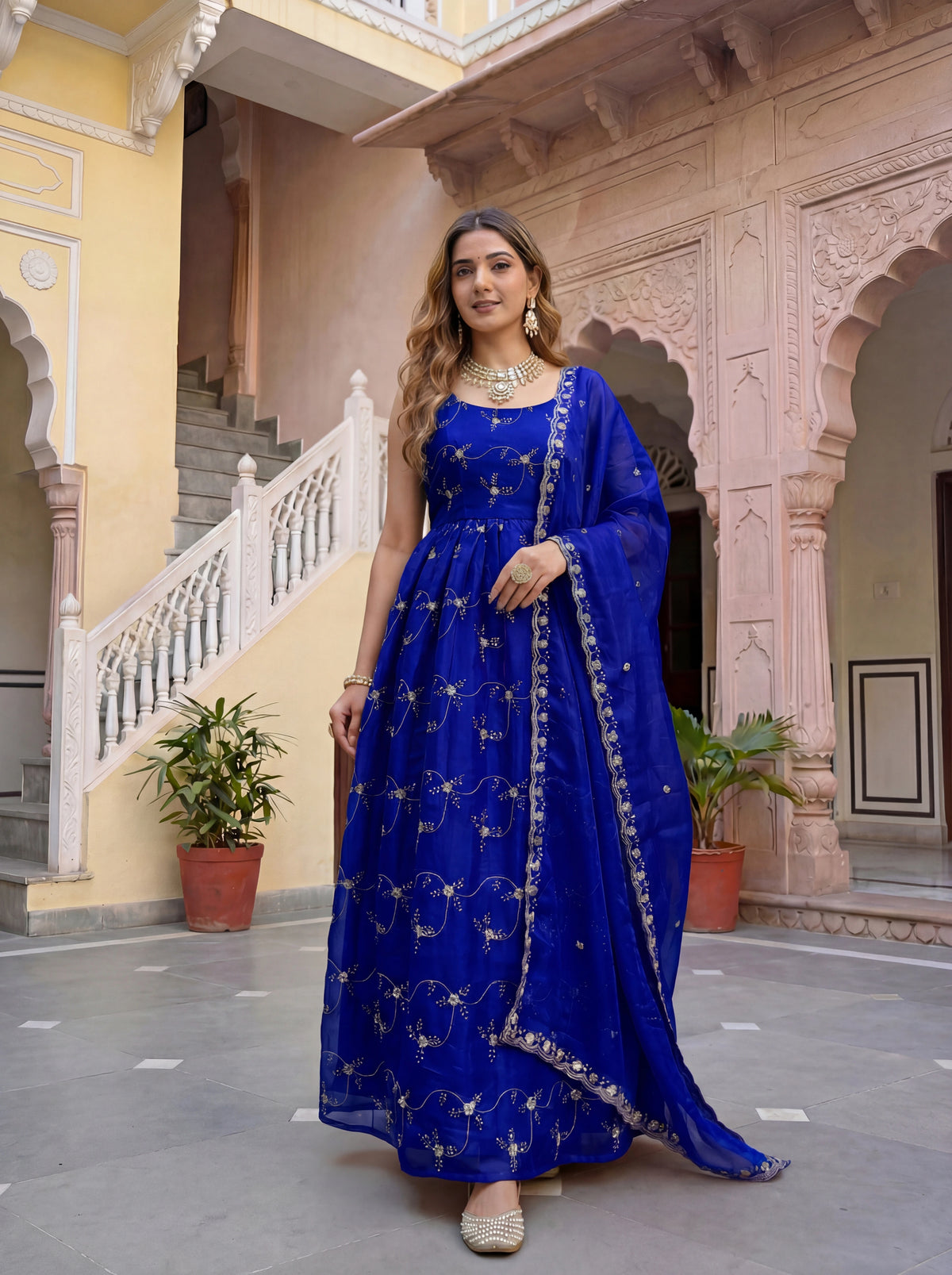 Woman in a blue traditional outfit standing in an architectural setting