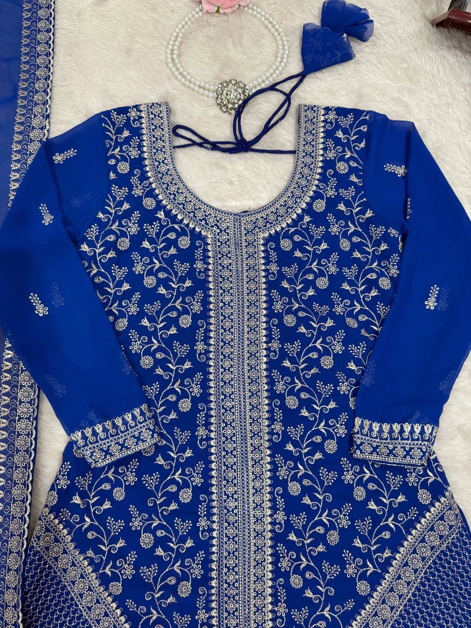 Blue embroidered traditional outfit with white patterns on a light background