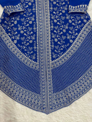 Blue fabric with intricate white embroidery on a white background