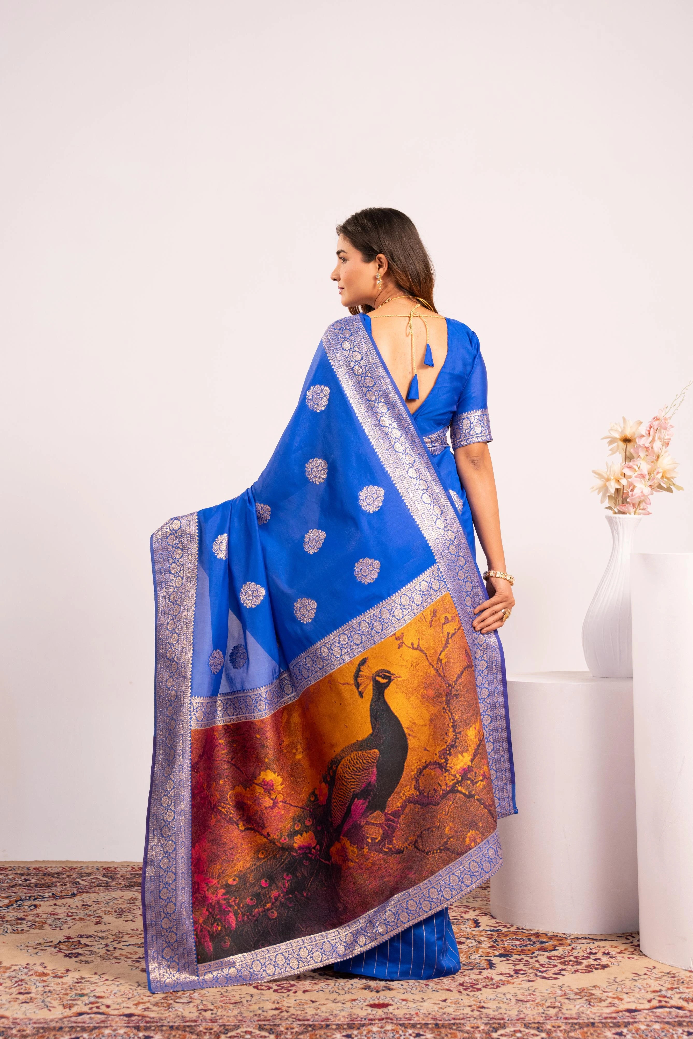 Woman wearing a blue saree with a peacock design on a white background