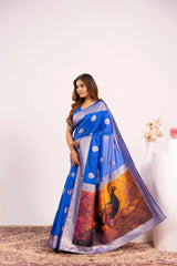 Woman wearing a blue saree with a scenic design on a white background