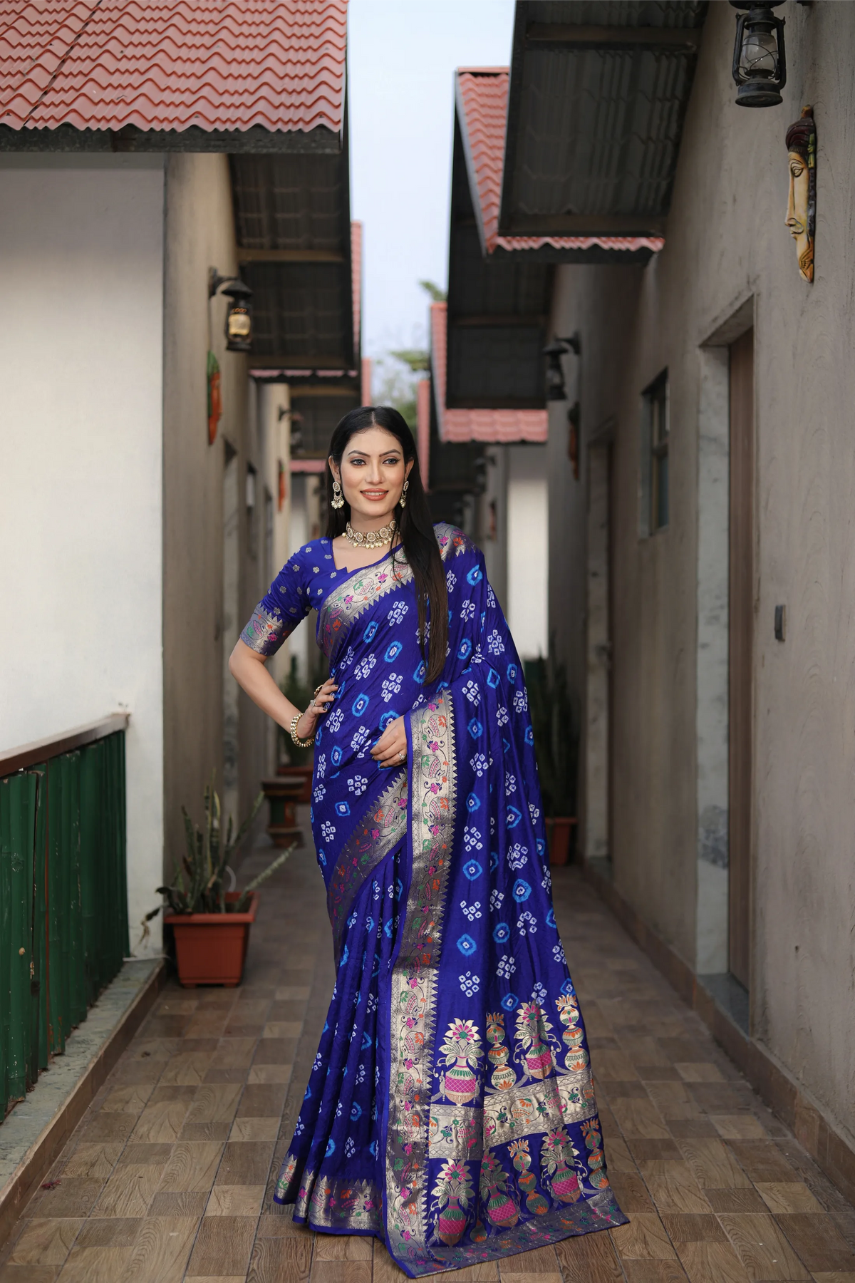 Woman in a blue saree standing in a narrow alleyway.