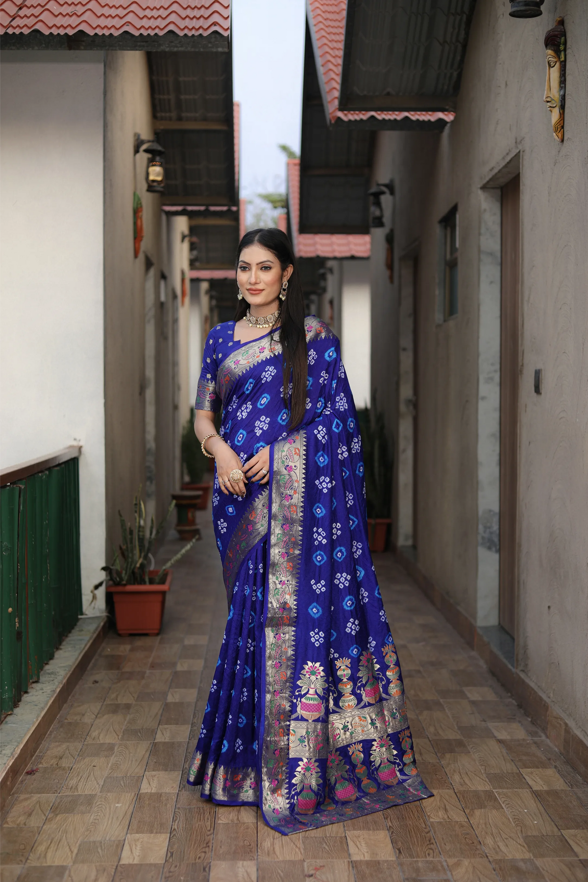 Woman in a blue saree standing in a narrow alleyway.