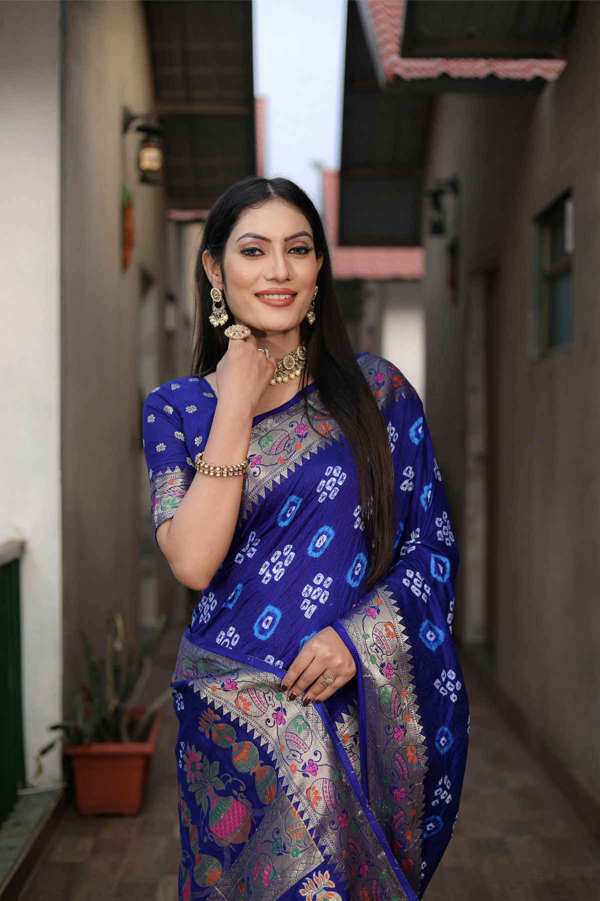 Woman in a blue saree with floral patterns standing in an outdoor setting.