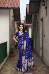 Woman in a blue saree standing in a narrow alleyway.