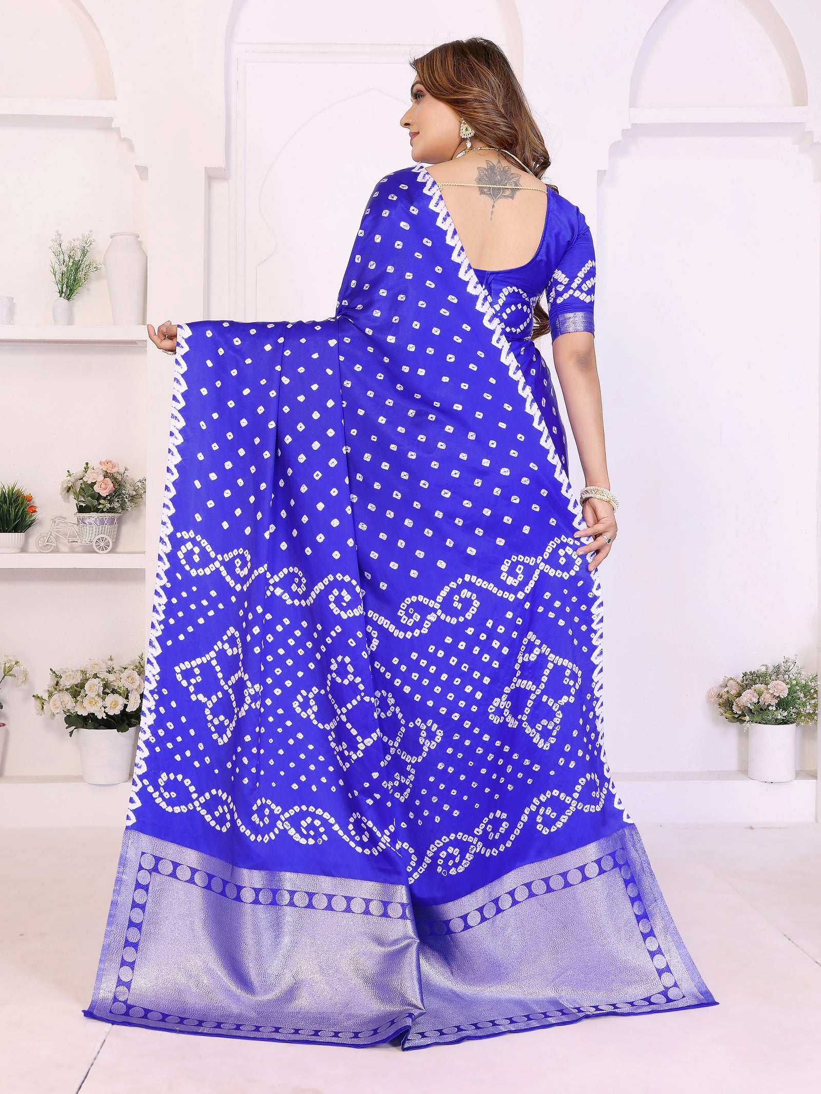 Woman wearing a blue saree with white patterns in a minimalistic setting