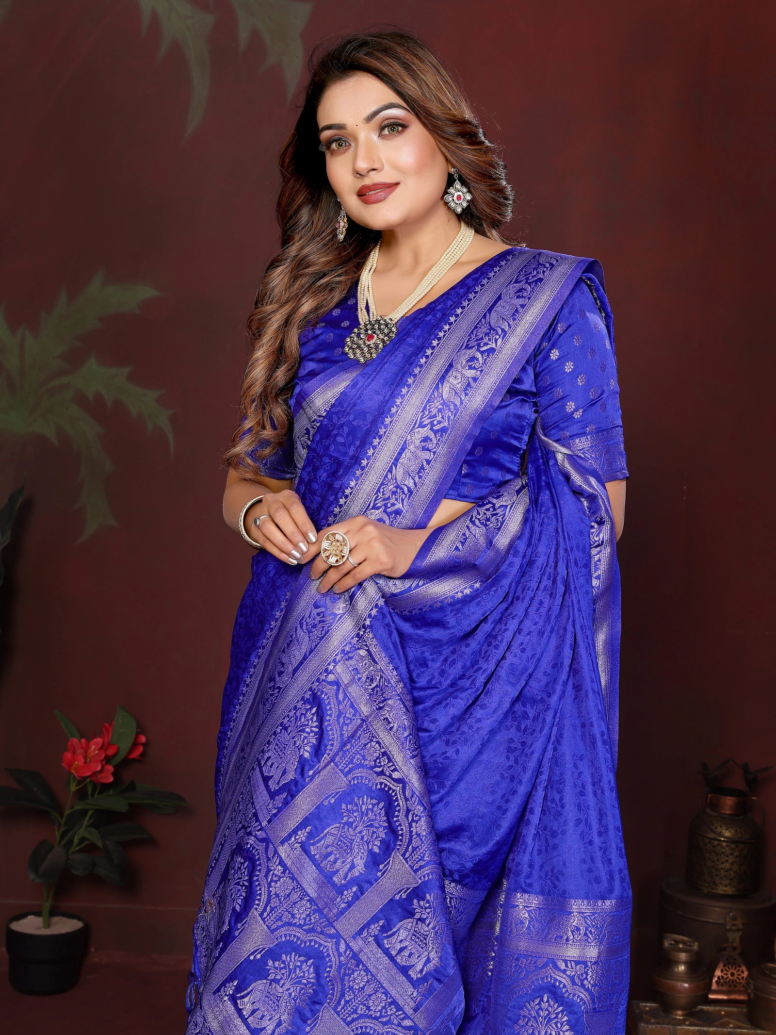 Woman wearing a blue saree with intricate patterns against a dark background