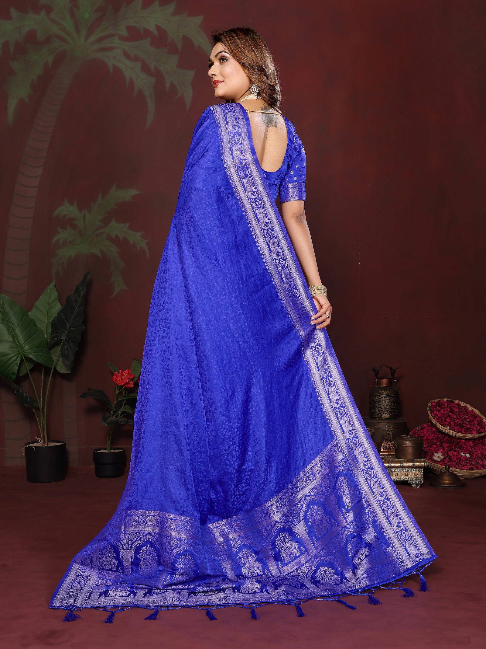 Woman wearing a blue saree with a decorative border against a dark background
