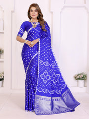 Woman wearing a blue saree with white patterns in a white room.