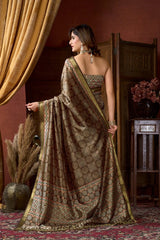 Woman in a traditional saree standing in a room with decorative elements.