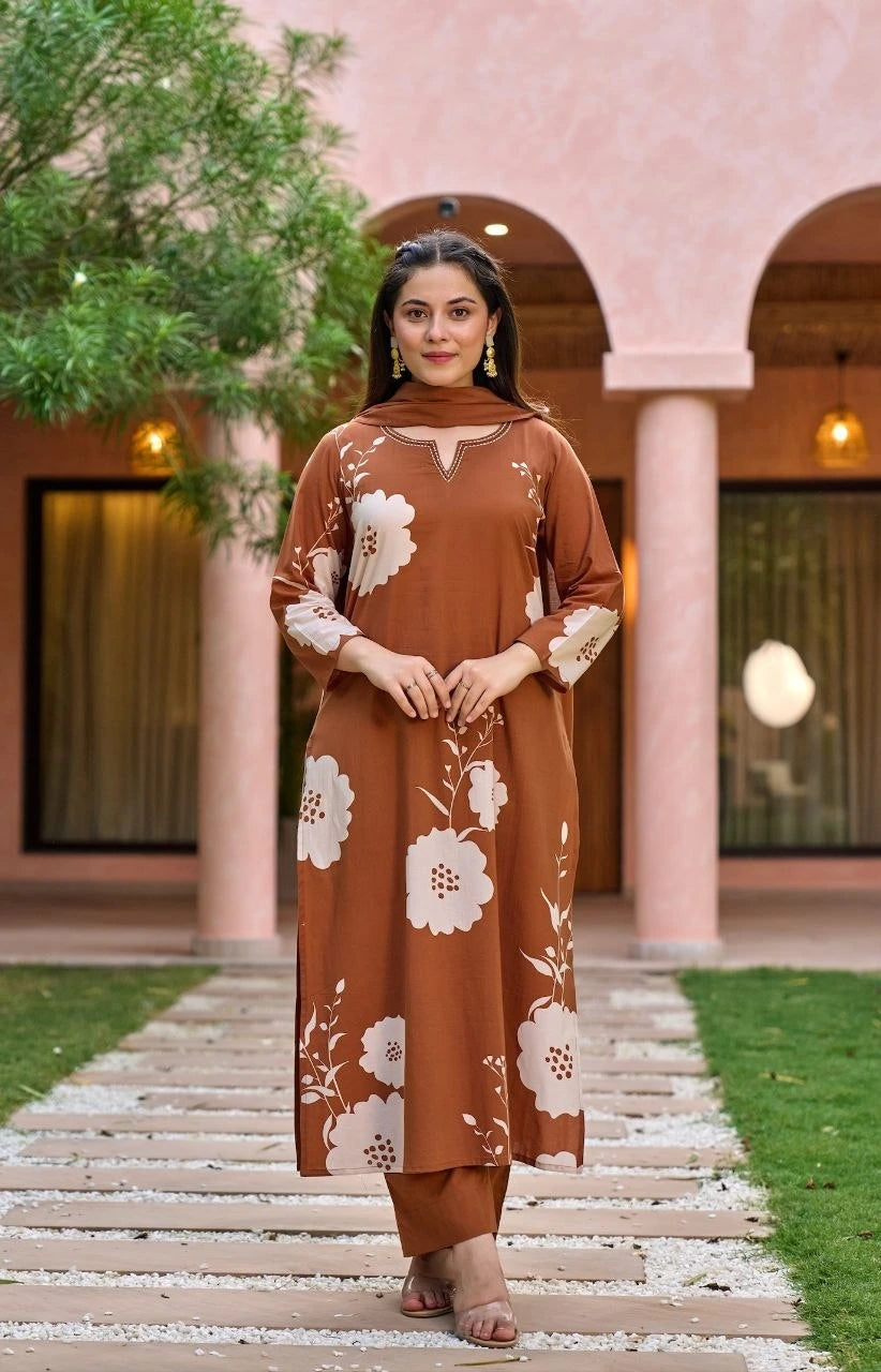 Woman in a brown floral outfit standing on a pathway with a building in the background
