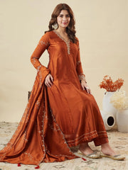Woman wearing a rust-colored traditional outfit with intricate designs on a beige background