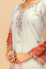 Close-up of a white and peach traditional outfit with intricate embroidery on a beige background