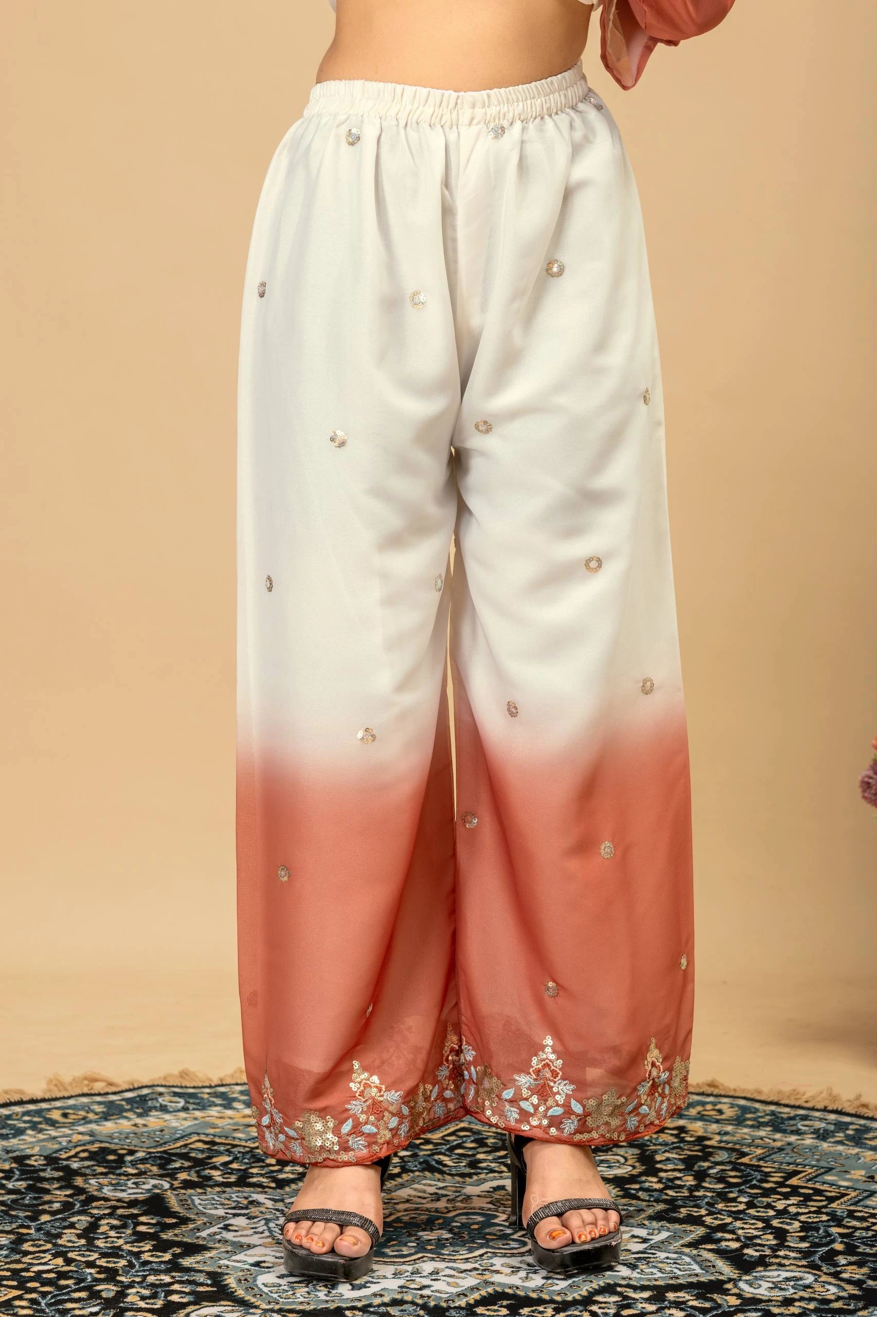 White and pink gradient pants with floral embroidery on a beige background