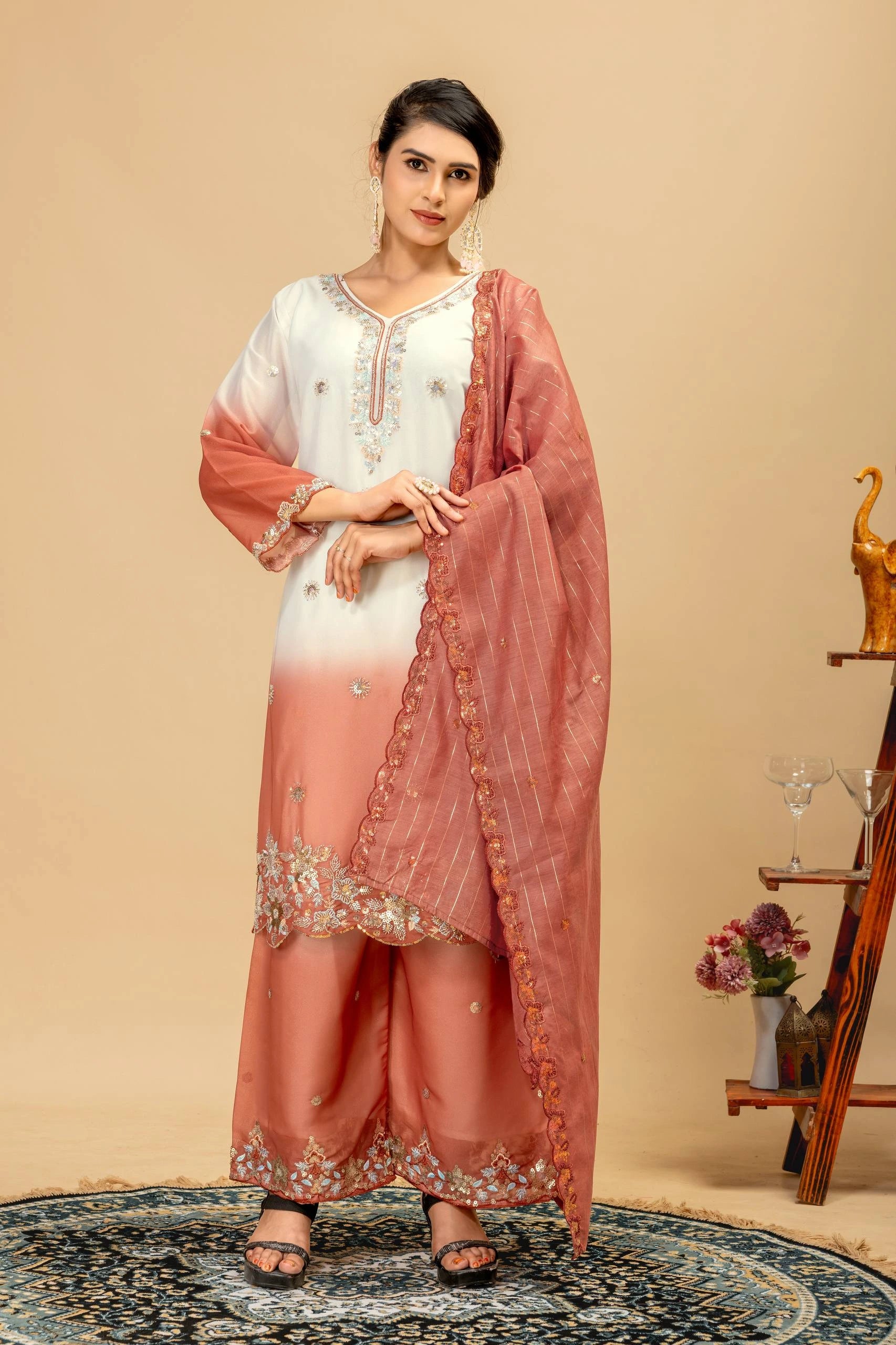 Woman wearing a peach and white traditional outfit with a matching dupatta against a beige background.