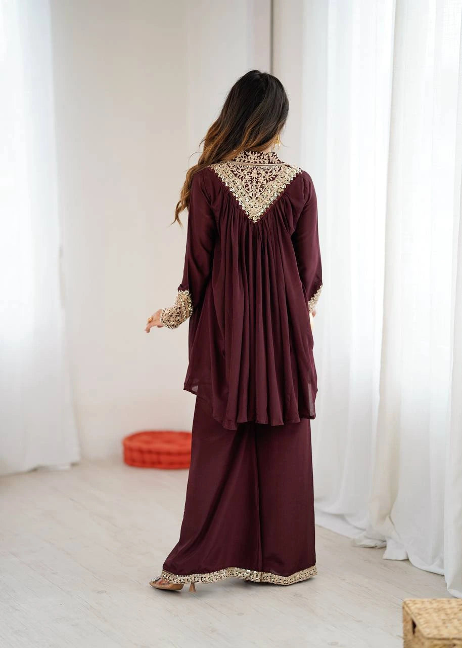 Woman wearing a burgundy outfit with intricate lace details in a minimalistic setting.