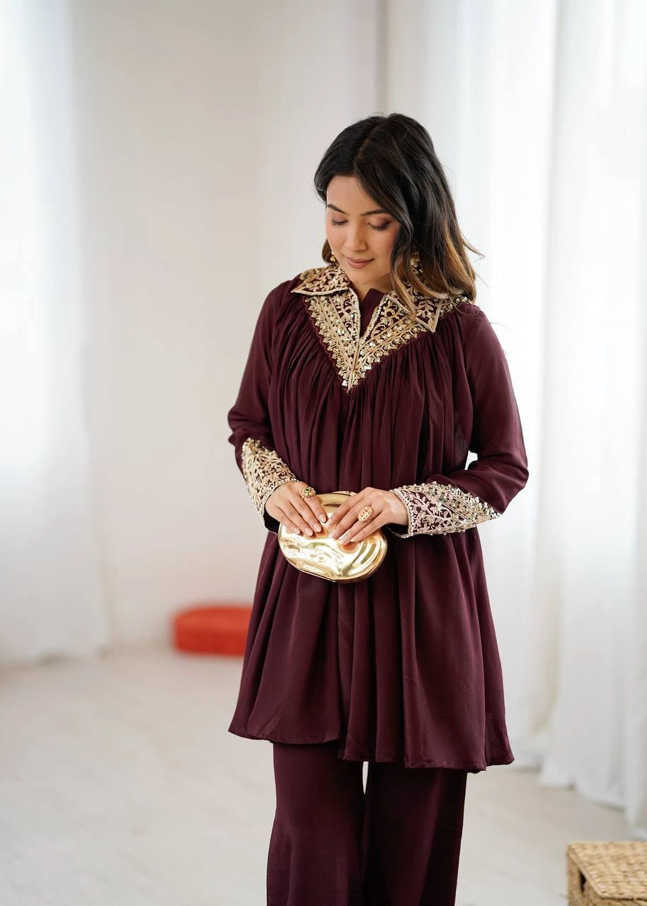 Woman wearing a burgundy outfit with gold embellishments holding a gold clutch.