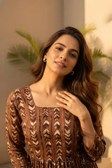 Woman wearing a brown patterned dress with a blurred indoor background