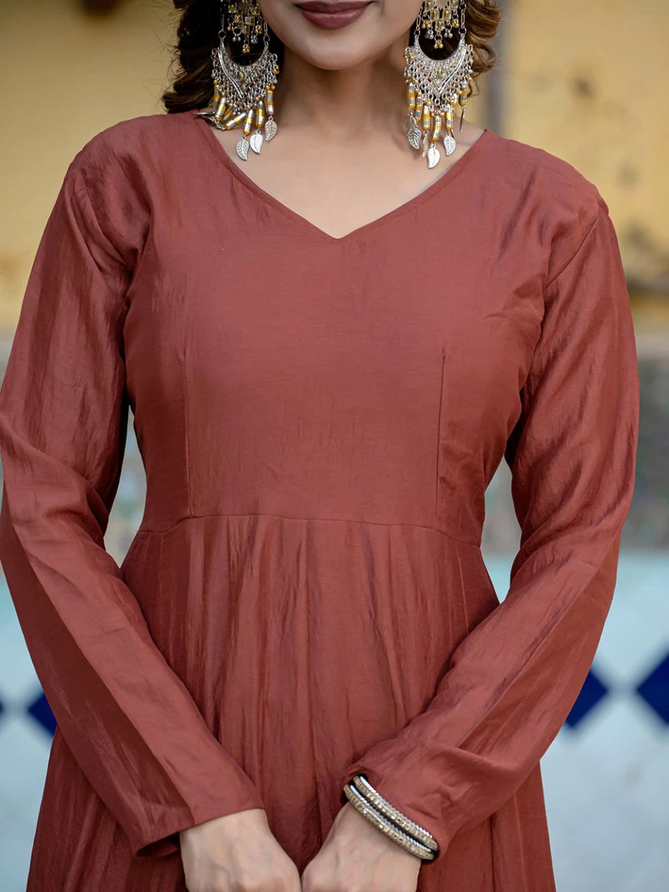 Person wearing a rust-colored dress with long sleeves and a blurred background