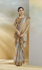 Woman wearing a beige saree with a plain background